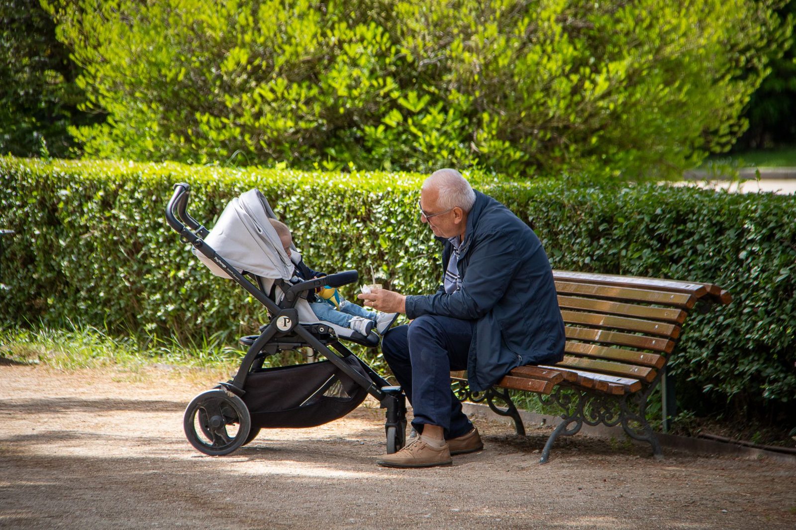 Grandparent with a pram on a park bench