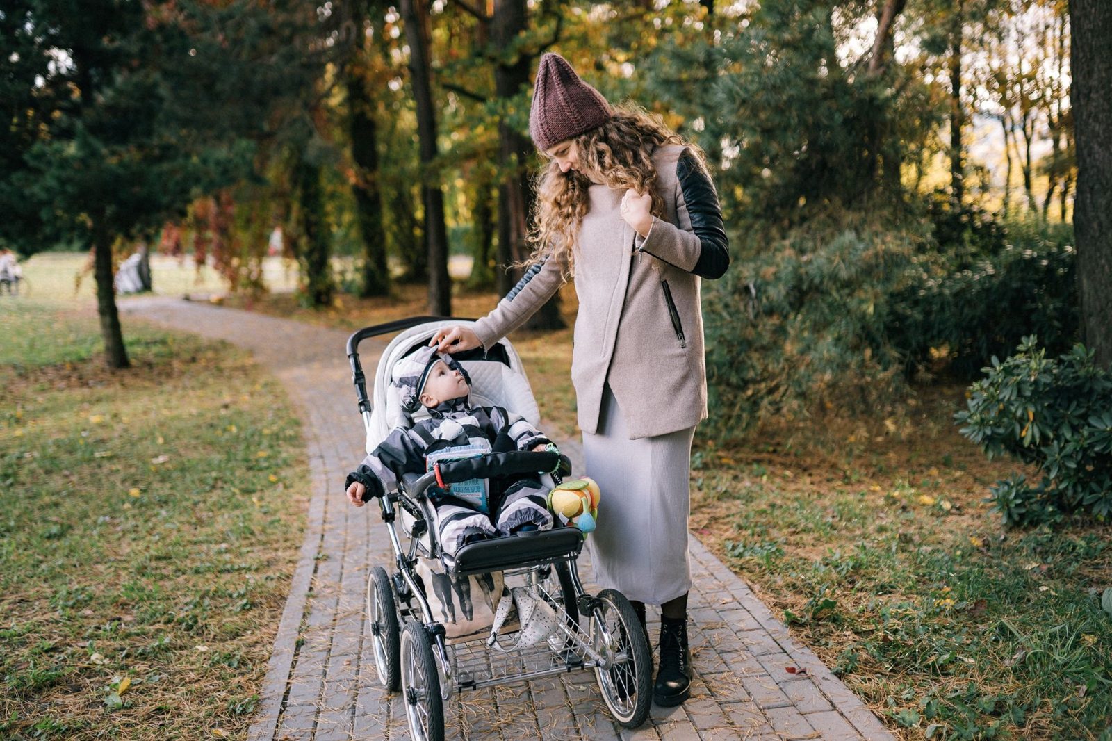Mother pushing a stroller along a park path