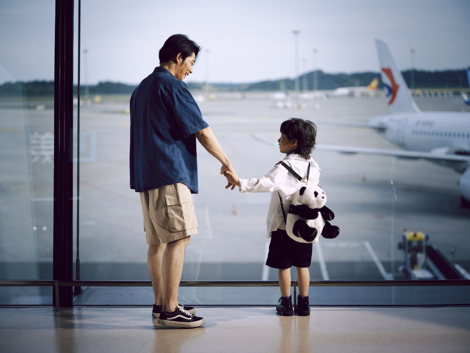 Father and child looking out at an airport