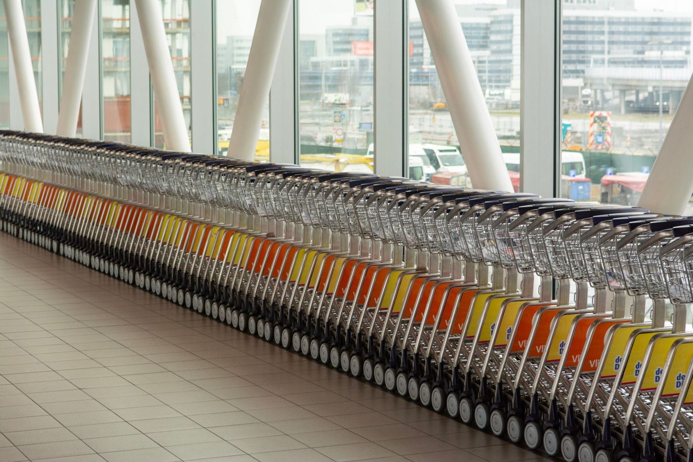 A long row of luggage trolleys lined up inside an airport terminal